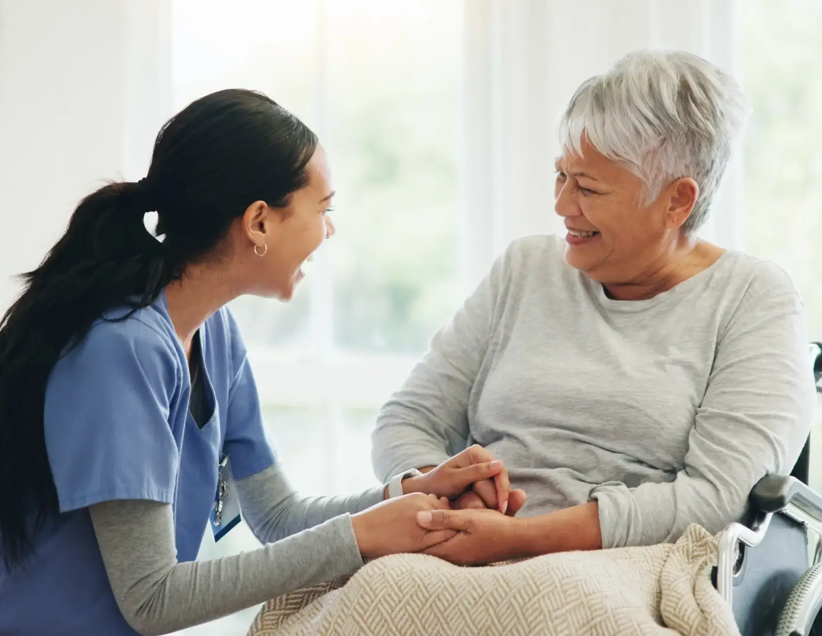 Caregiver and elderly woman sharing a laugh.